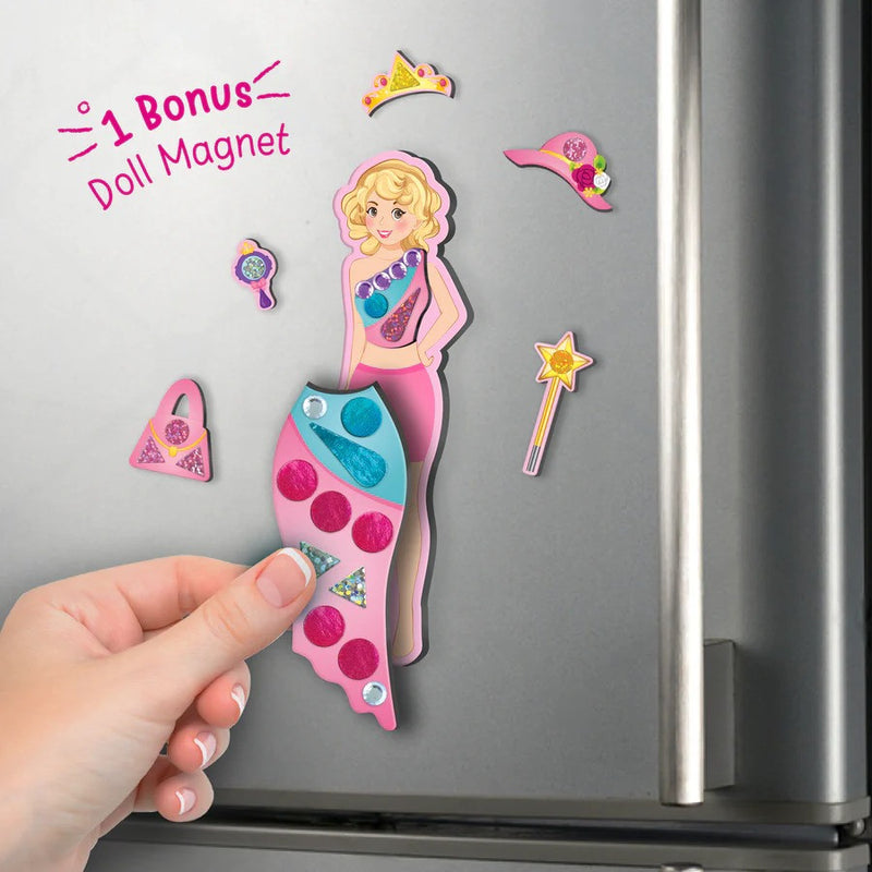 Mermaid-shaped magnet with accessories on a refrigerator door, labeled with '1 Bonus Doll Magnet'.