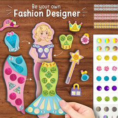 Fashion design kit with a mermaid figure and decorative elements on a wooden surface.