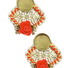 Pair of ornate earrings with red floral elements on a white background