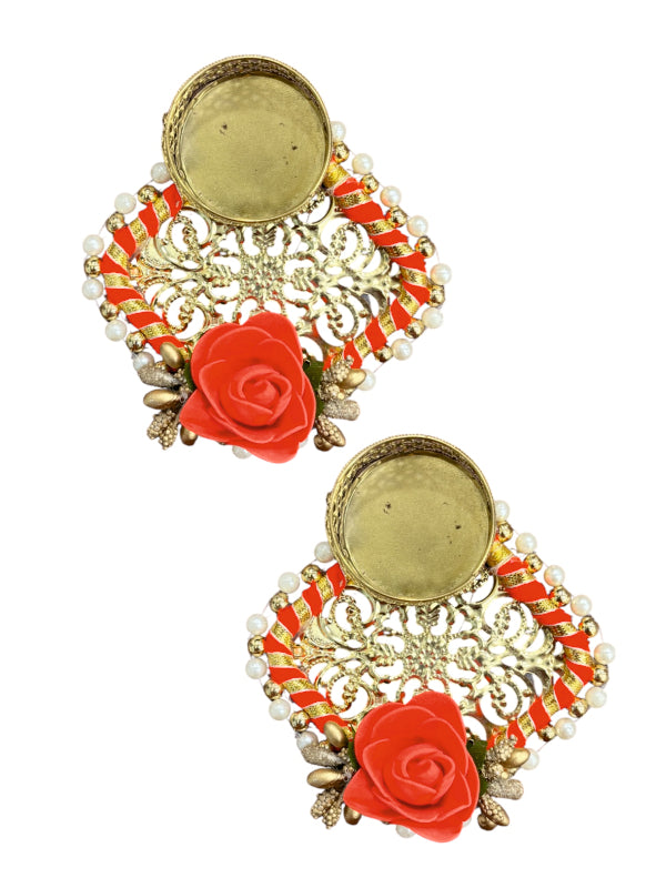 Pair of ornate earrings with red floral elements on a white background