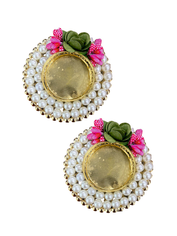 Pair of earrings with pearl-like beads and floral decorations on a white background