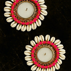 Pair of earrings with white shell-like design, pink and gold circular accents on a dark background