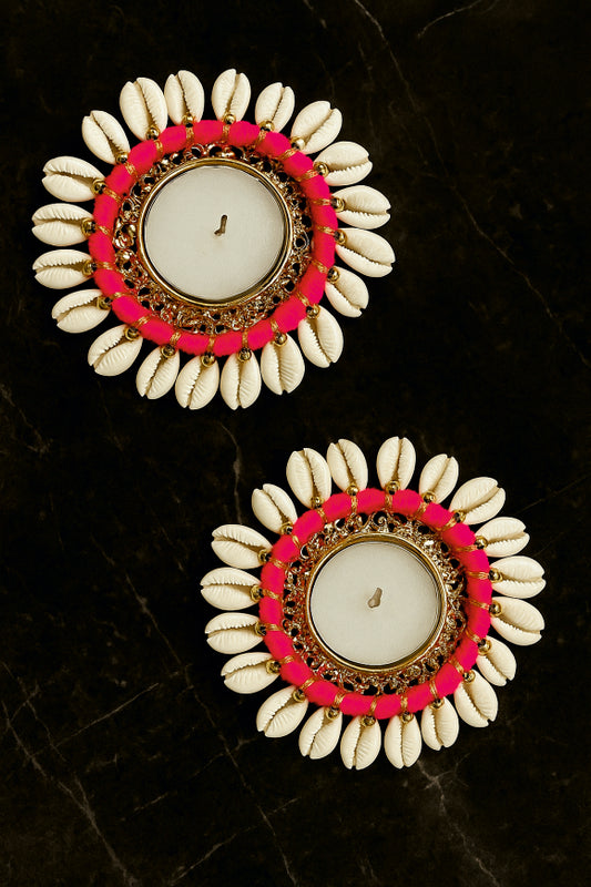 Pair of earrings with white shell-like design, pink and gold circular accents on a dark background