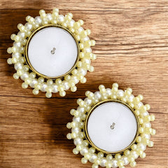 Two pearl-framed candles on a wooden surface