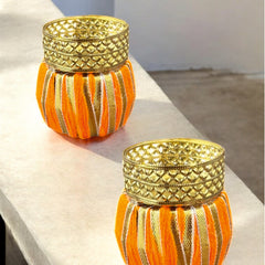 Two decorative candle holders with gold tops on a white surface.