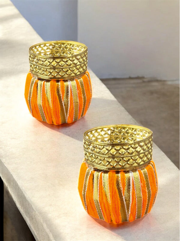 Two decorative candle holders with gold tops on a white surface.