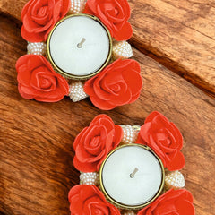 Decorative candle holders with red flowers and pearls on a wooden surface