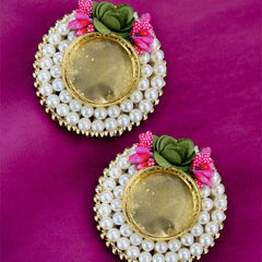 Pair of earrings with pearl and gold details on a purple background
