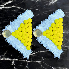 Heart-shaped earrings with yellow beads and blue 'N' shapes on a black marble background