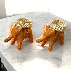 Two decorative elephant figurines with gold accents on a marble surface.