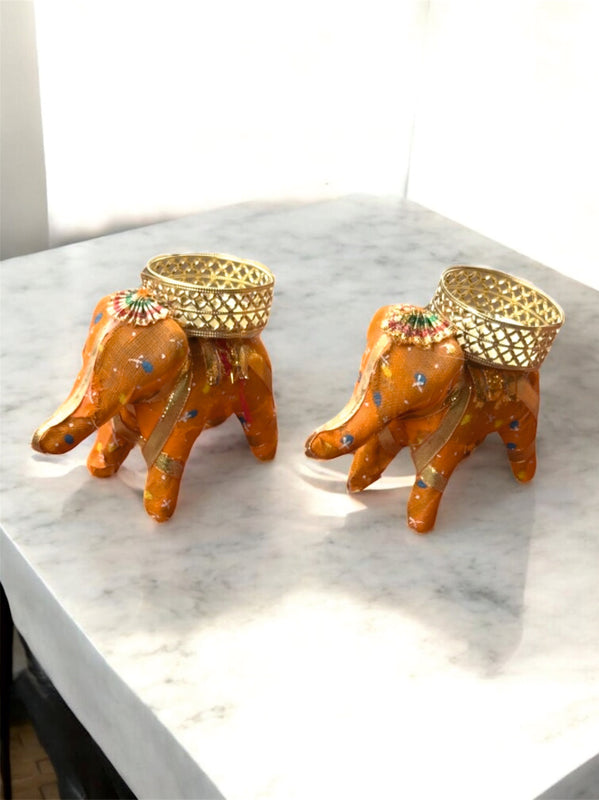 Two decorative elephant figurines with gold accents on a marble surface.