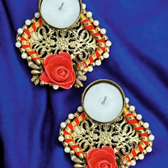 Decorative candles with gold floral designs and red roses on a blue fabric background
