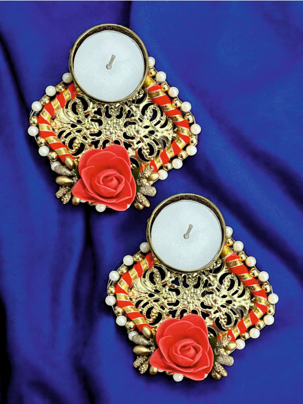 Decorative candles with gold floral designs and red roses on a blue fabric background