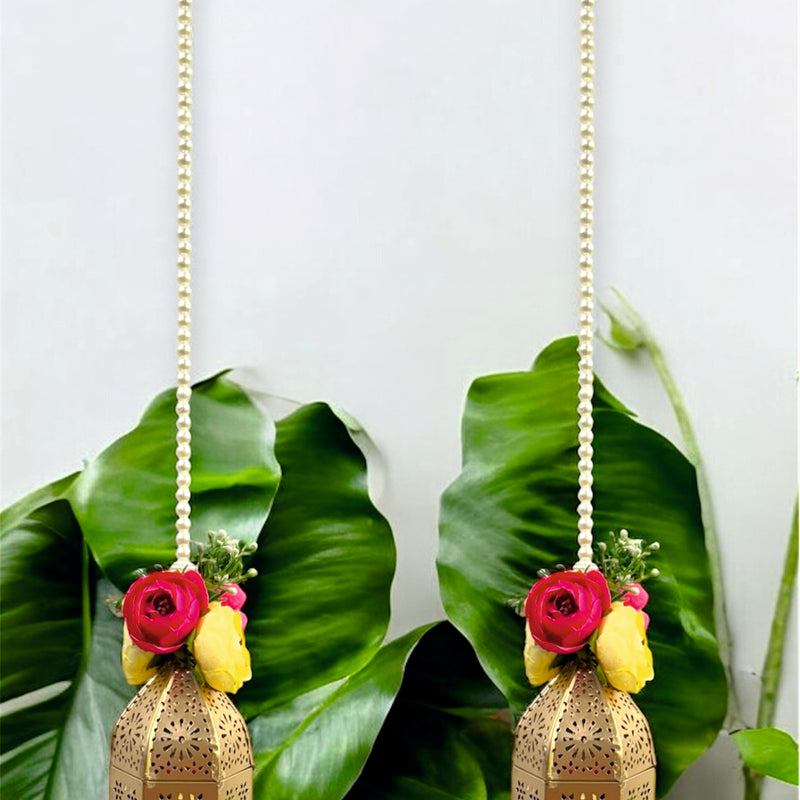 Two decorative hanging lanterns with floral elements on a green leaf background