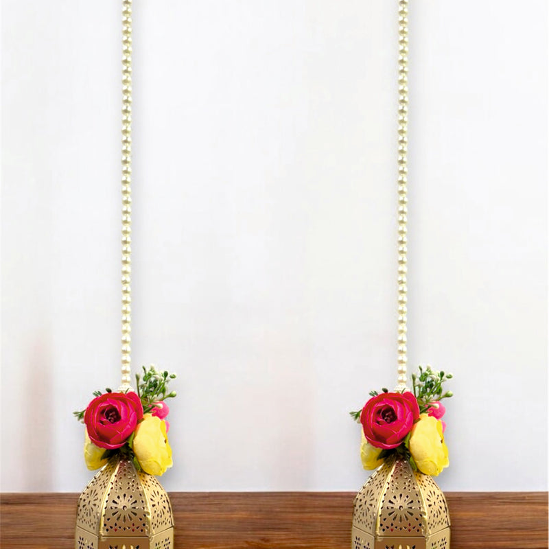 Two decorative hanging lanterns with floral arrangements on a wooden surface.