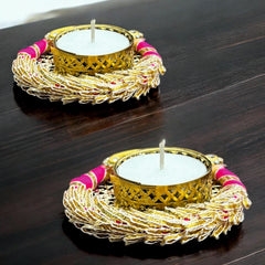Two decorative candle holders with gold and pink accents on a dark surface.