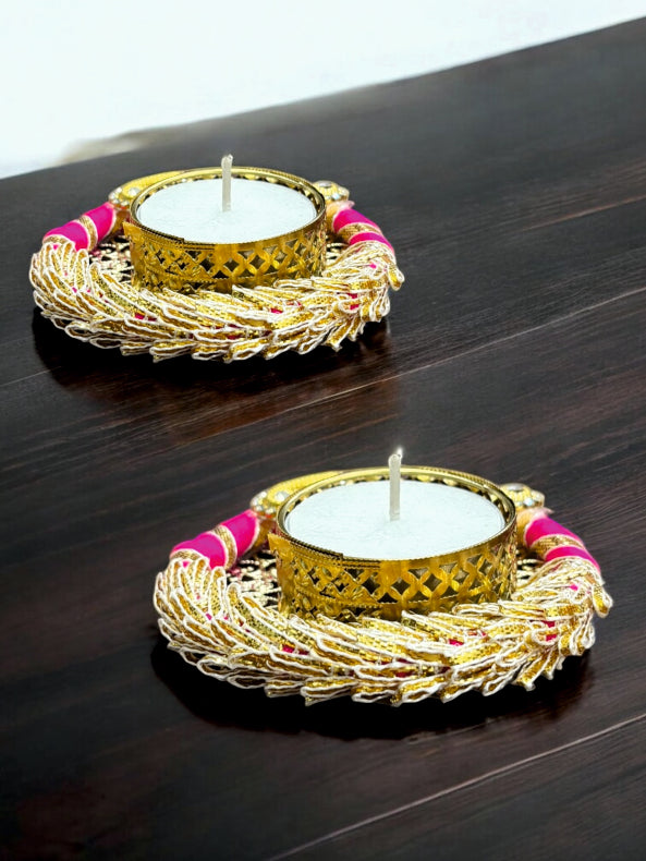 Two decorative candle holders with gold and pink accents on a dark surface.