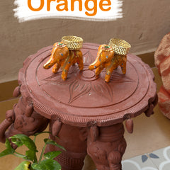 Decorative object with elephants and a table, featuring orange elements.