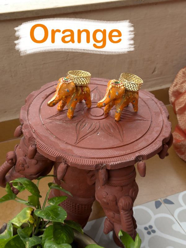 Decorative object with elephants and a table, featuring orange elements.