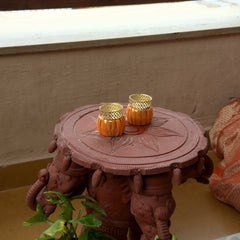 Decorative table with gold candle holders on a light-colored floor.
