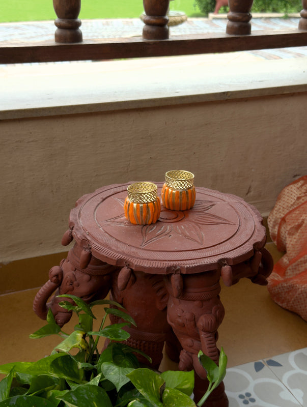 Decorative table with gold candle holders on a light-colored floor.