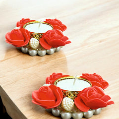 Decorative candle holders with red rose designs on a wooden surface
