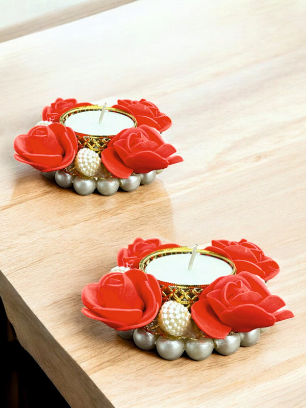 Decorative candle holders with red rose designs on a wooden surface