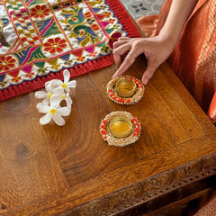 Decorative setting with colorful fabric, flowers, and traditional items on a wooden table.