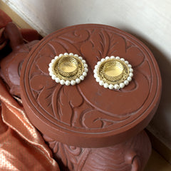 Gold earrings with pearl accents on a decorative red box.