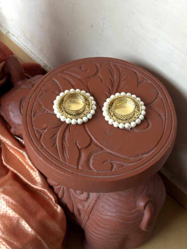 Gold earrings with pearl accents on a decorative red box.
