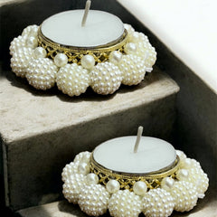 Two pearl-adorned candles on a stone surface