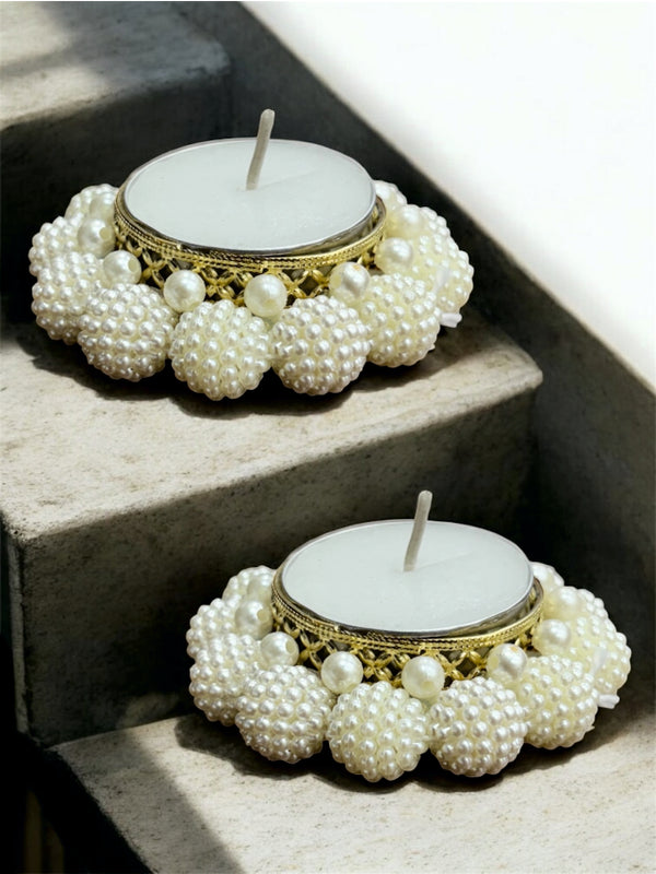 Two pearl-adorned candles on a stone surface