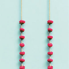 Two long necklaces with pink beads and gold chains on a light blue background
