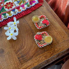Decorative items including a colorful embroidered fabric, flowers, and ornate coasters on a wooden surface.