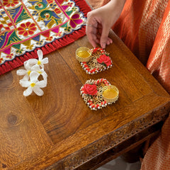 Decorative earrings on a wooden table with a colorful embroidered cloth in the background