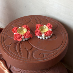 Pair of pink floral earrings with gold centers on a decorative brown box.
