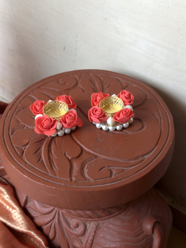Pair of pink floral earrings with gold centers on a decorative brown box.