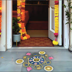 Decorative entrance with floral garlands and colorful rangoli on a floor.