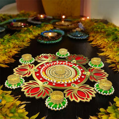 Decorative rangoli design with colorful patterns on a black surface, surrounded by candles and flowers.