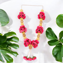 Necklace with pink flowers and gold beads on a white background with green leaves.