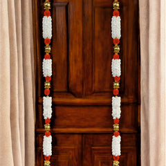 Decorative door hanging with red and white flowers on a wooden door.
