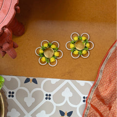 Decorative earrings on a brown surface with a patterned floor in the background