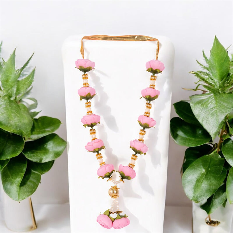 Pink floral earrings on a white stand with green plants on either side.