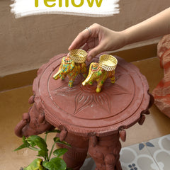 Decorative stand with elephants on top, held by a hand, with 'Yellow' text overlay.