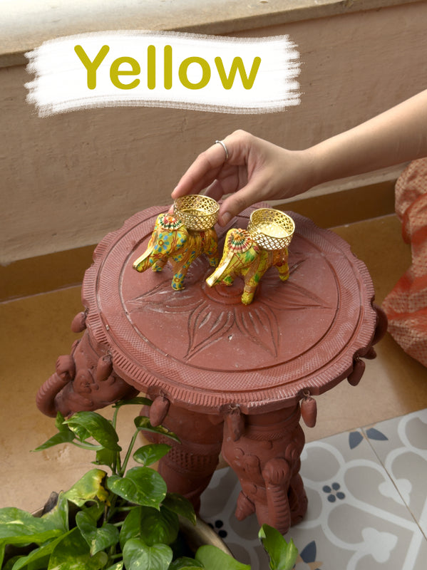 Decorative stand with elephants on top, held by a hand, with 'Yellow' text overlay.