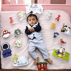 Child in a suit surrounded by winter-themed decorations and stickers on a pink bed.
