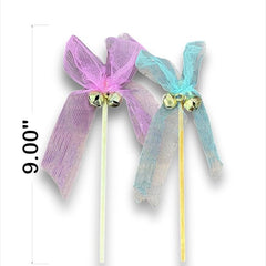 Two decorative bows on sticks with bells, one pink and one blue, on a white background.