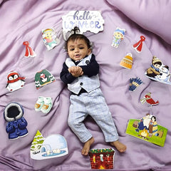 Baby in a suit surrounded by winter-themed illustrations on a purple blanket