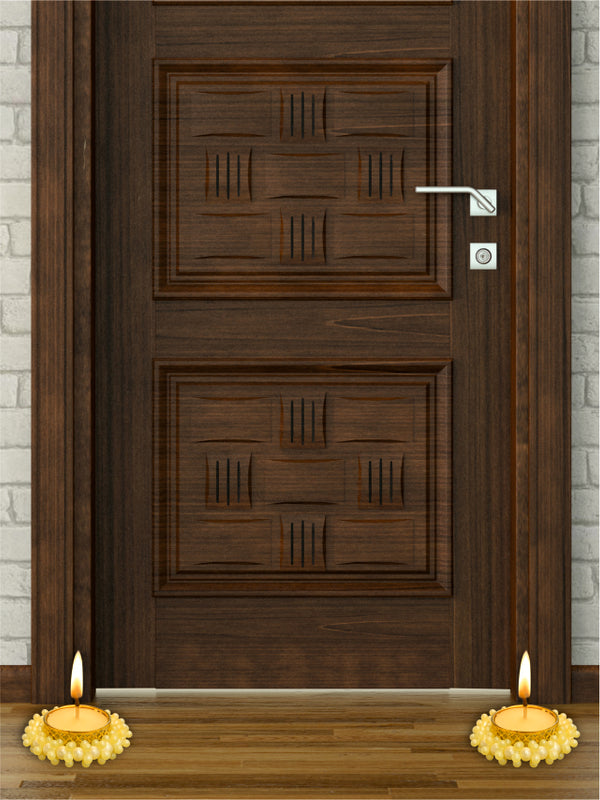 Wooden door with two lit candles on a wooden floor in front of it.