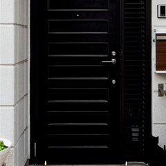 Black door with decorative elements on a stone pavement